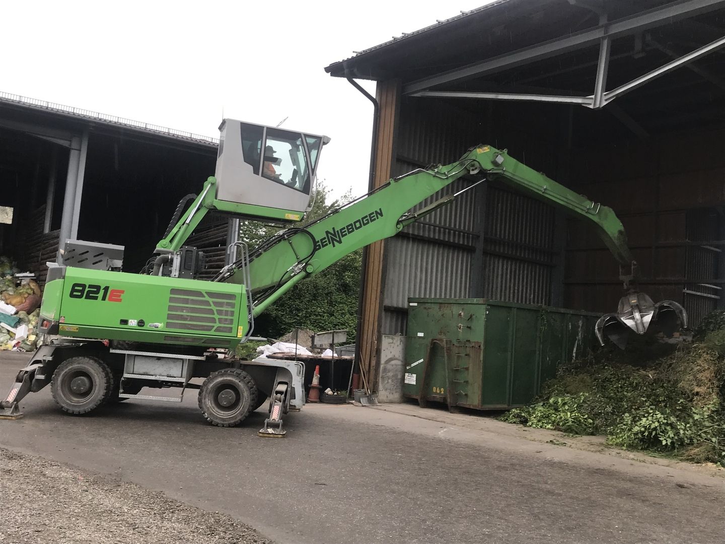 Eine grüne Maschine arbeitet auf einem Wertstoffhof
